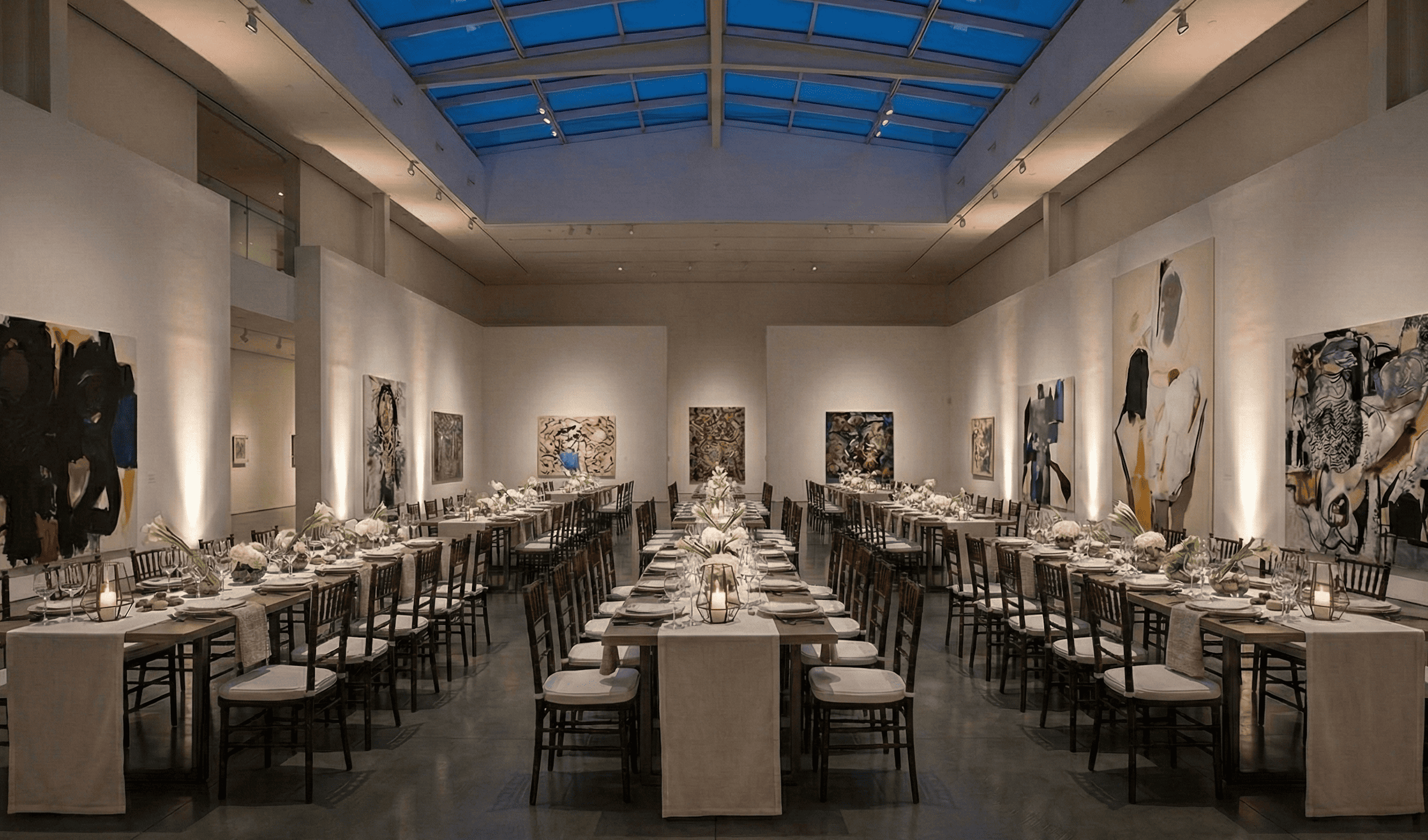 Spacious elegant gallery with high ceilings with long tables set for a formal dinner event